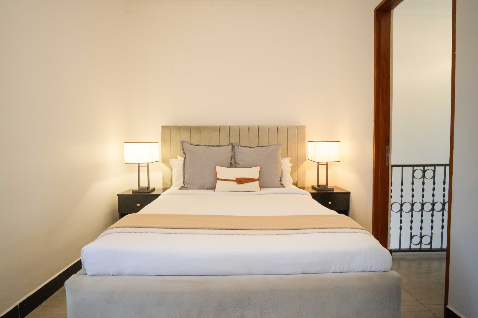 Blue Sapphire apartment bedroom with upholstered headboard and bedside lamps